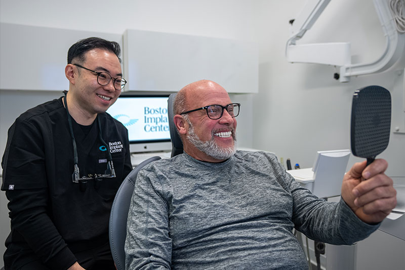 doctor looking into mirror with patient after dental procedure